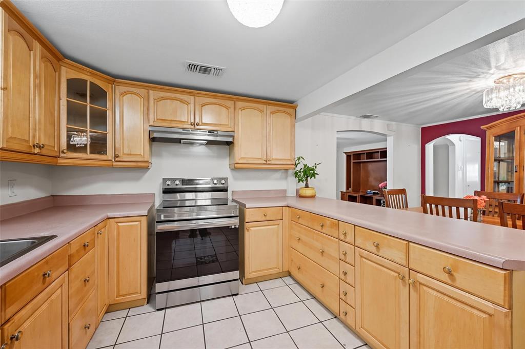 3334 Sheldon Avenue Dallas, TX 75211 - Photo 6 of 22 Kitchen featuring electric range, glass insert cabinets, light countertops, and light brown cabinetry