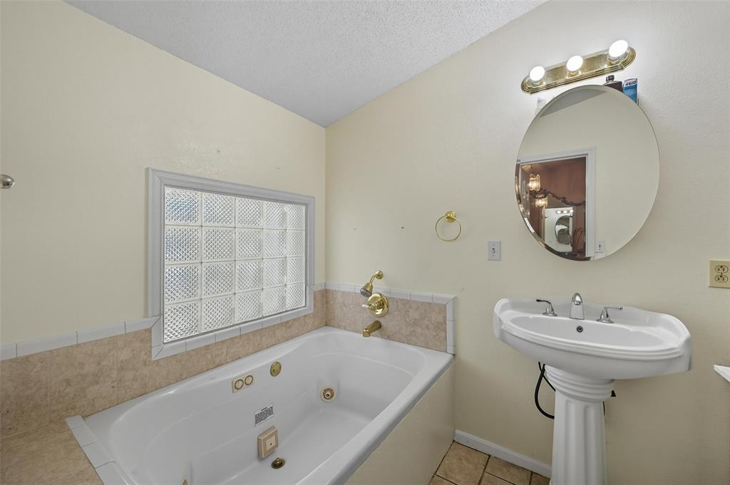 3334 Sheldon Avenue Dallas, TX 75211 - Photo 7 of 22 Bathroom with a whirlpool tub, light tile patterned flooring, washer / clothes dryer, a textured ceiling, and lofted ceiling