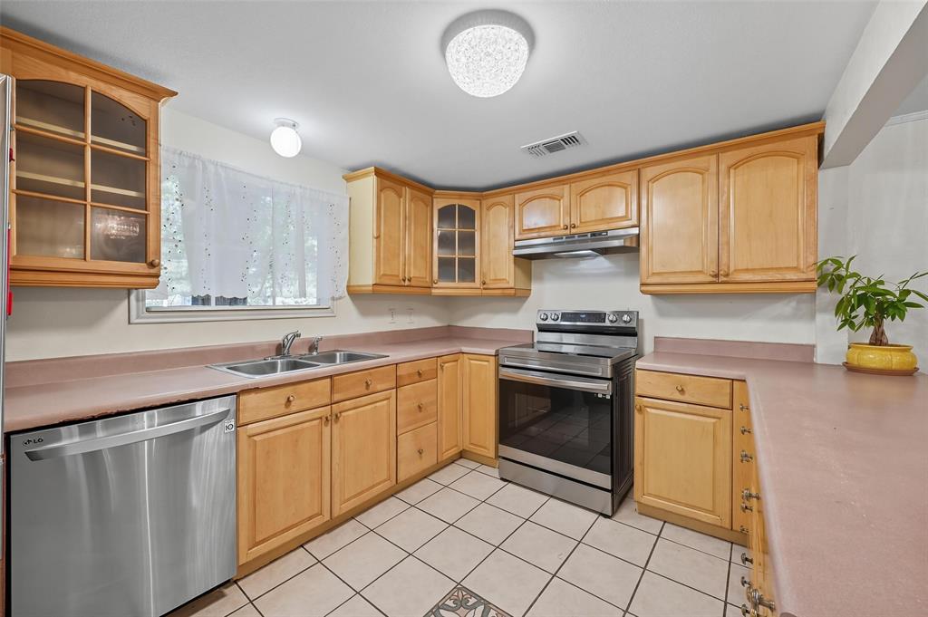 3334 Sheldon Avenue Dallas, TX 75211 - Photo 8 of 22 Kitchen with glass insert cabinets, appliances with stainless steel finishes, light brown cabinetry, light tile patterned floors, and light countertops