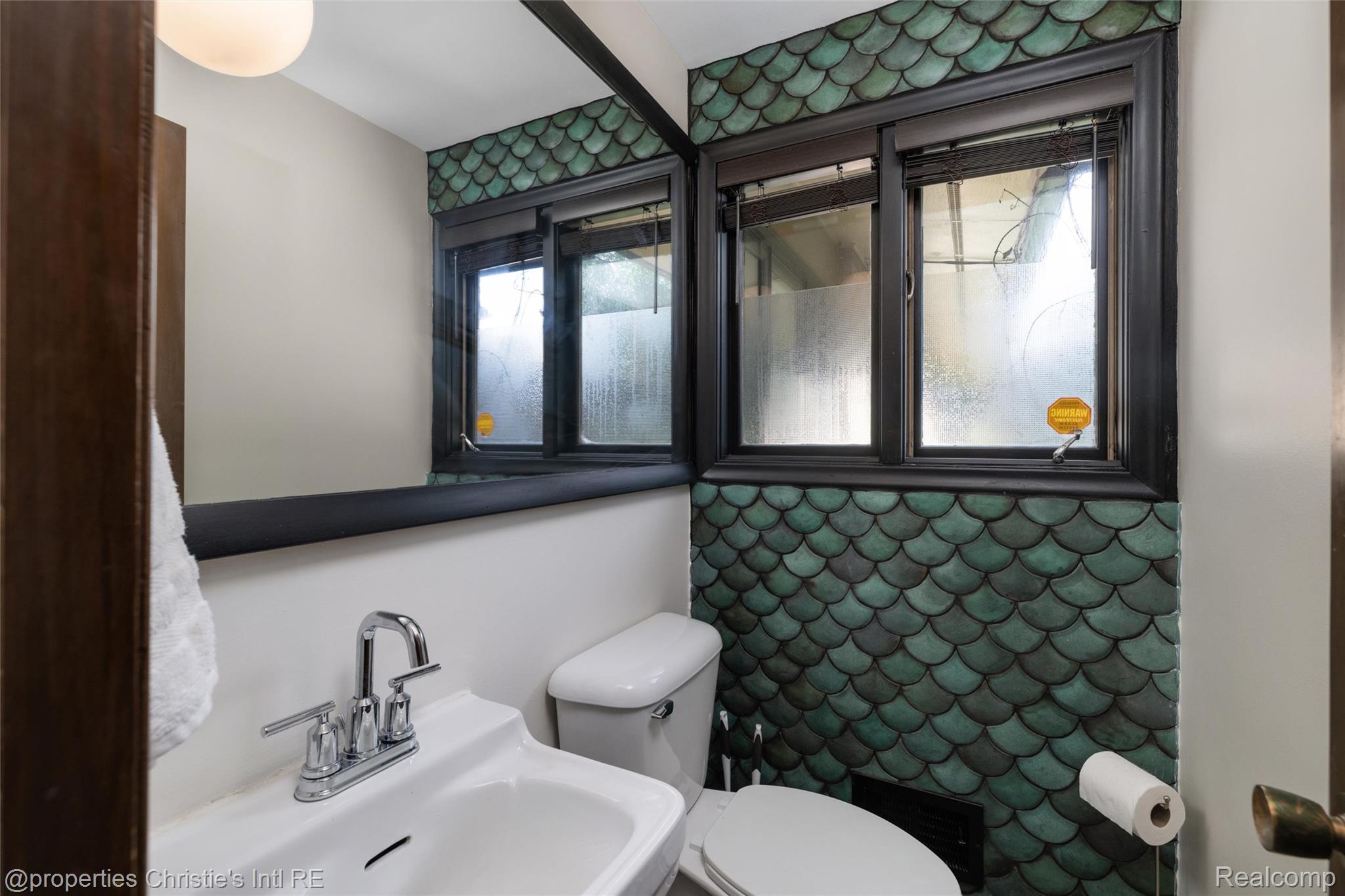 2771 West Seven Mile Road Detroit, MI 48221 - Photo 27 of 57 Powder room featuring mermaid-scale wall tile, a large mirror, and a white pedestal sink with a chrome faucet