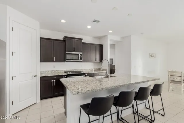 a kitchen with kitchen island granite countertop a sink and a stove top oven with wooden floor