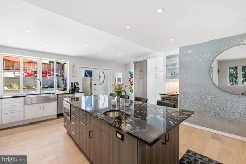 a large white kitchen with stainless steel appliances kitchen island granite countertop a lot of counter space and wooden floor