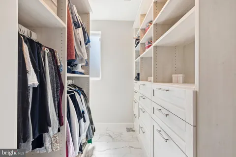 a view of walk in closet with clothes and shoes