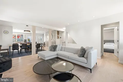 a living room with furniture a rug kitchen view and a window