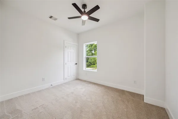 an empty room with a window and a fan