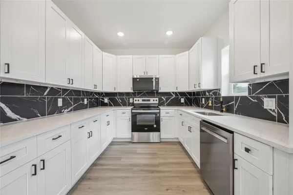 a kitchen with granite countertop white cabinets and stainless steel appliances