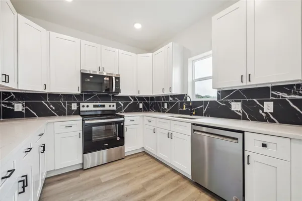 a kitchen with white cabinets and appliances
