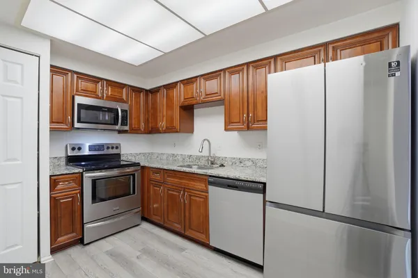 a kitchen with granite countertop a refrigerator stove top oven a sink and dishwasher