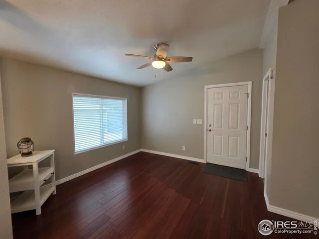 a view of an empty room with a window and wooden floor