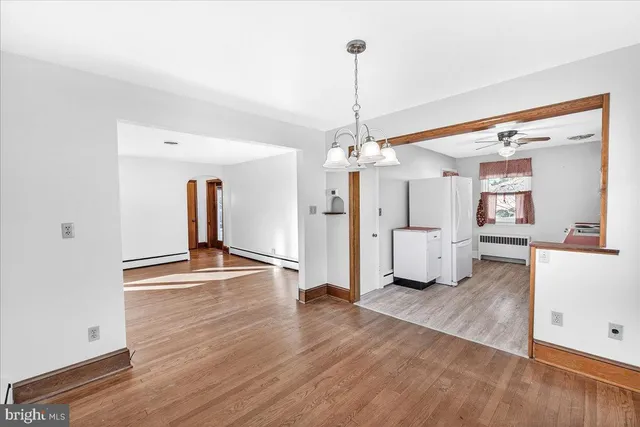 a view of a room with wooden floor and kitchen view