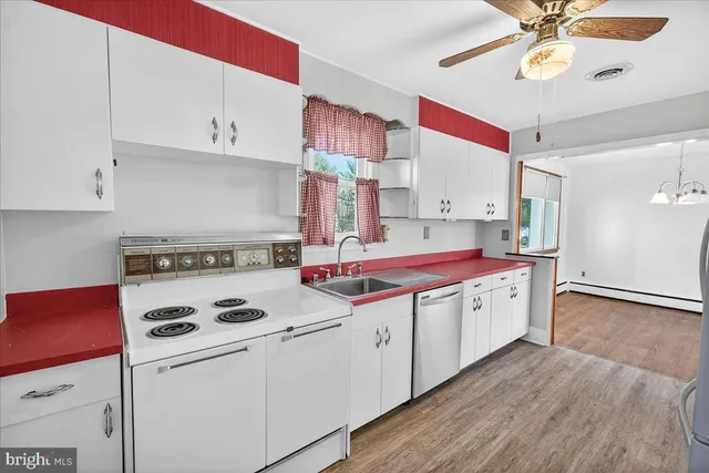 a kitchen with kitchen island granite countertop a sink a stove and white cabinets