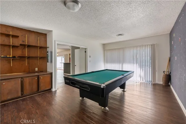 a room with wooden floors pool table and windows