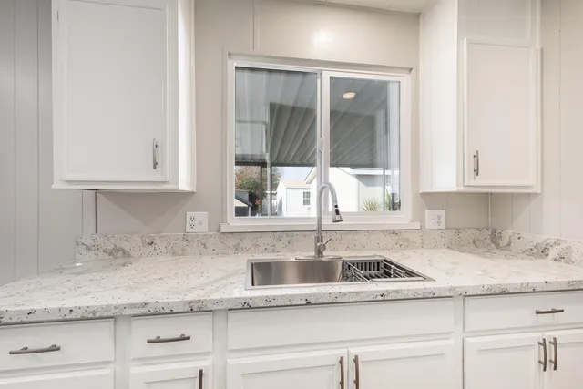 a kitchen with granite countertop white cabinets and a sink