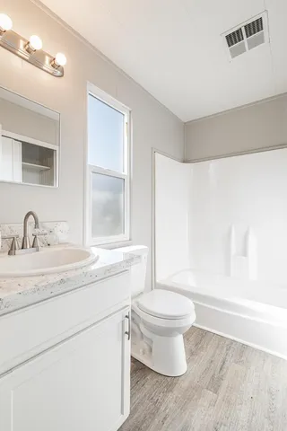 a bathroom with a granite countertop sink a toilet and a mirror