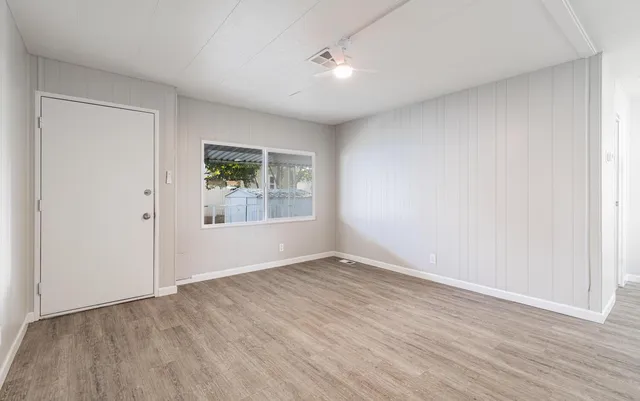 an empty room with wooden floor and windows