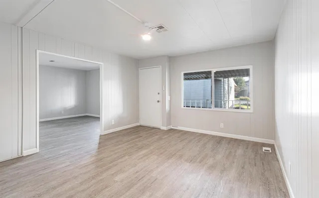 an empty room with wooden floor and windows