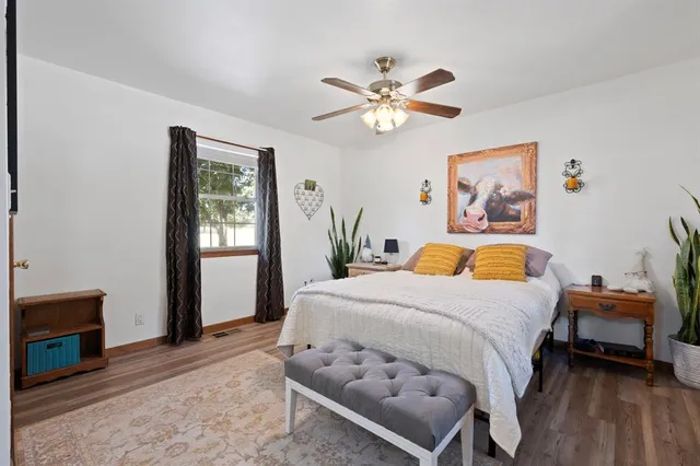a view of a bedroom with wooden floor and a ceiling fan