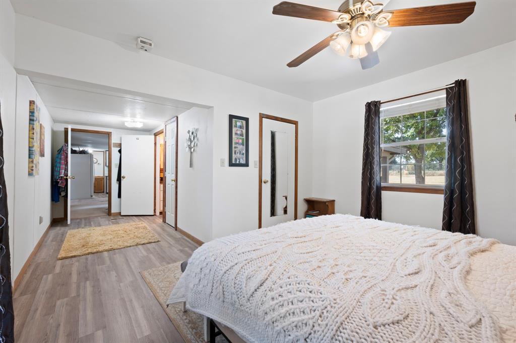 1500 County Road 404 Comanche, TX 76442 - Photo 24 of 39 a view of a bedroom with wooden floor and a ceiling fan