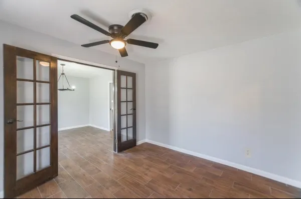 an empty room with windows and ceiling fan