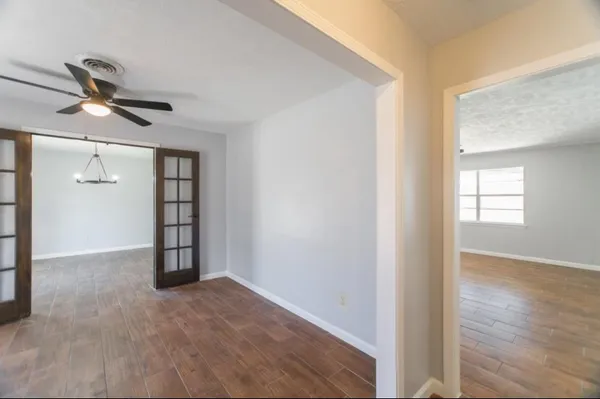 an empty room with wooden floor cabinet and windows