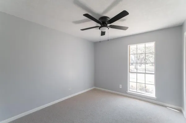 an empty room with a window and a fan