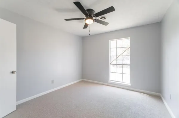 an empty room with a window and a fan