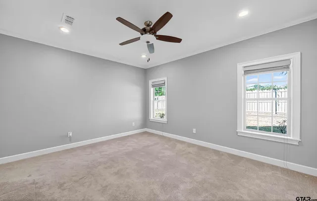 an empty room with windows and ceiling fan