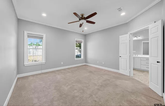 an empty room with windows and a ceiling fan