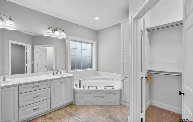 a bathroom with a tub sink double vanity granite and a mirror