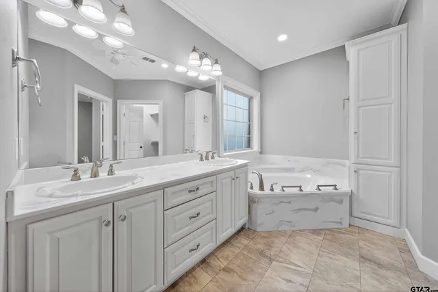 a bathroom with a granite countertop double vanity sink a mirror and a bathtub