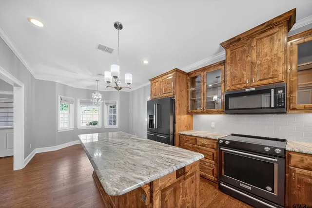 a kitchen with stainless steel appliances granite countertop a kitchen island a stove and a wooden cabinets