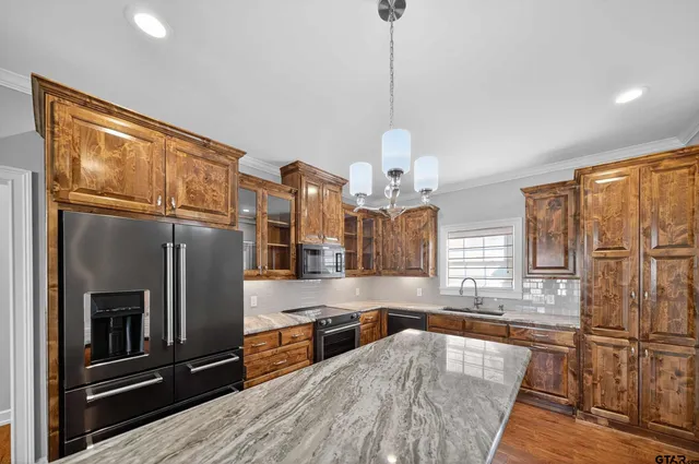 a large kitchen with stainless steel appliances granite countertop a refrigerator a oven and white cabinets with wooden floors