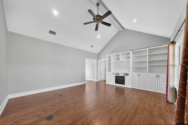 a view of an empty room with a window and wooden floor