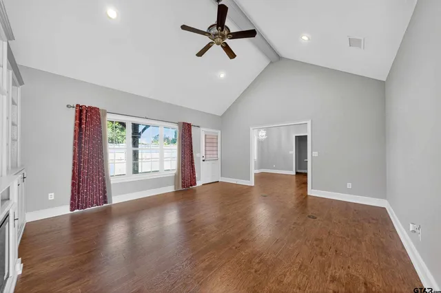 a view of an empty room with a window and wooden floor