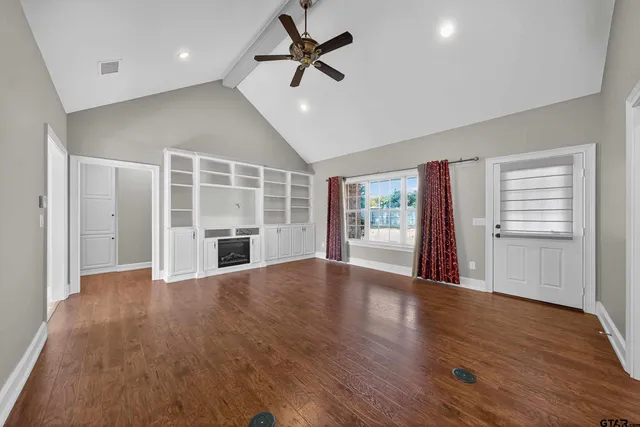 a view of an empty room with a window and wooden floor