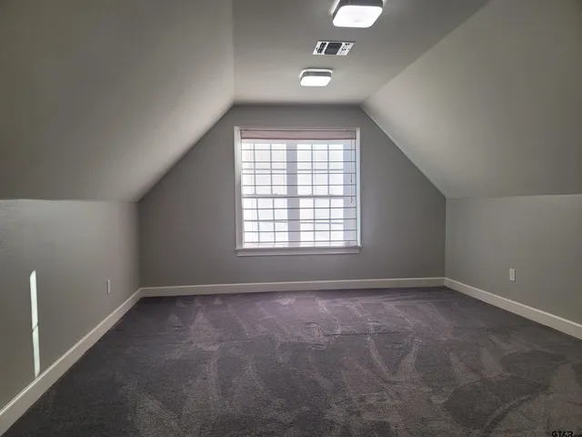an empty room with windows and chandelier fan