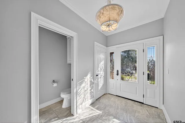 a view of a hallway to a room with wooden floor and a chandelier