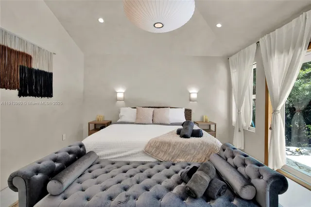 a bedroom with a large bed and a flat tv screen on dresser