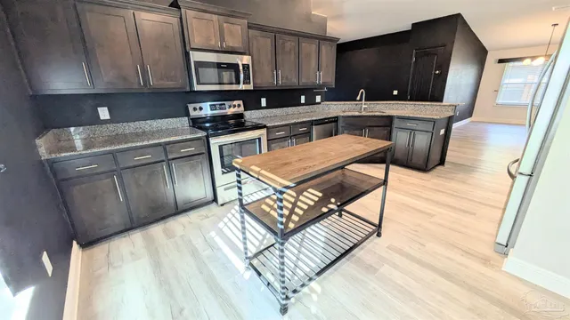 a kitchen with stainless steel appliances granite countertop a stove a sink a microwave a refrigerator and cabinets