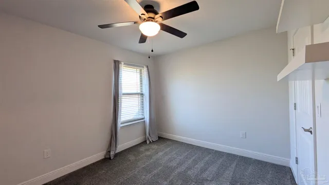 an empty room with windows and fan