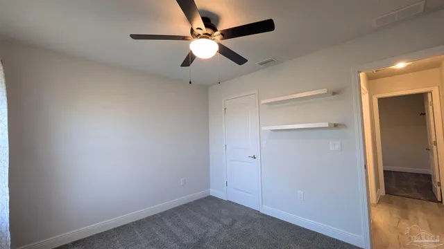 an empty room with a ceiling fan and a fan