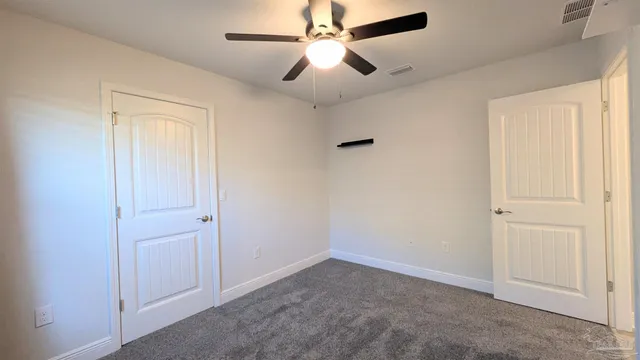 an empty room with closet and a chandelier fan