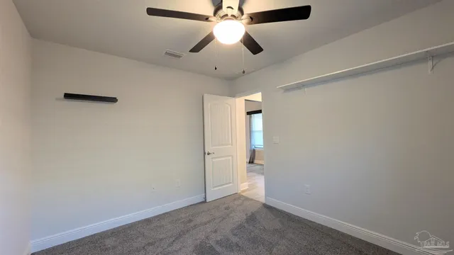an empty room with closet and a chandelier fan