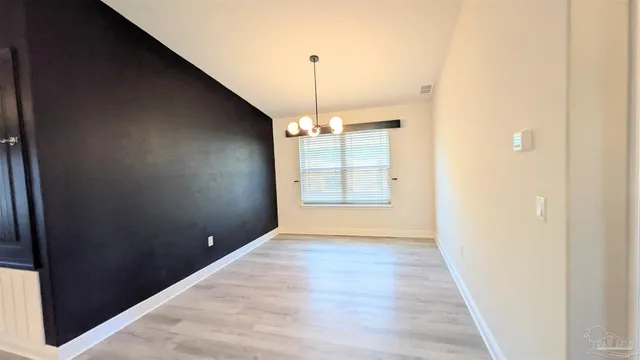 a view of a hallway with wooden floor and chandelier