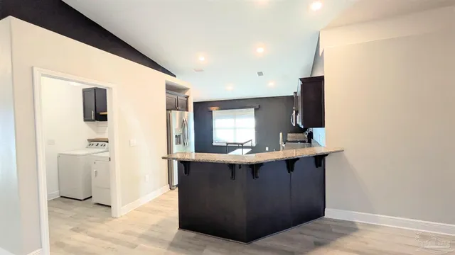 a view of kitchen island with sink wooden floor and refrigerator