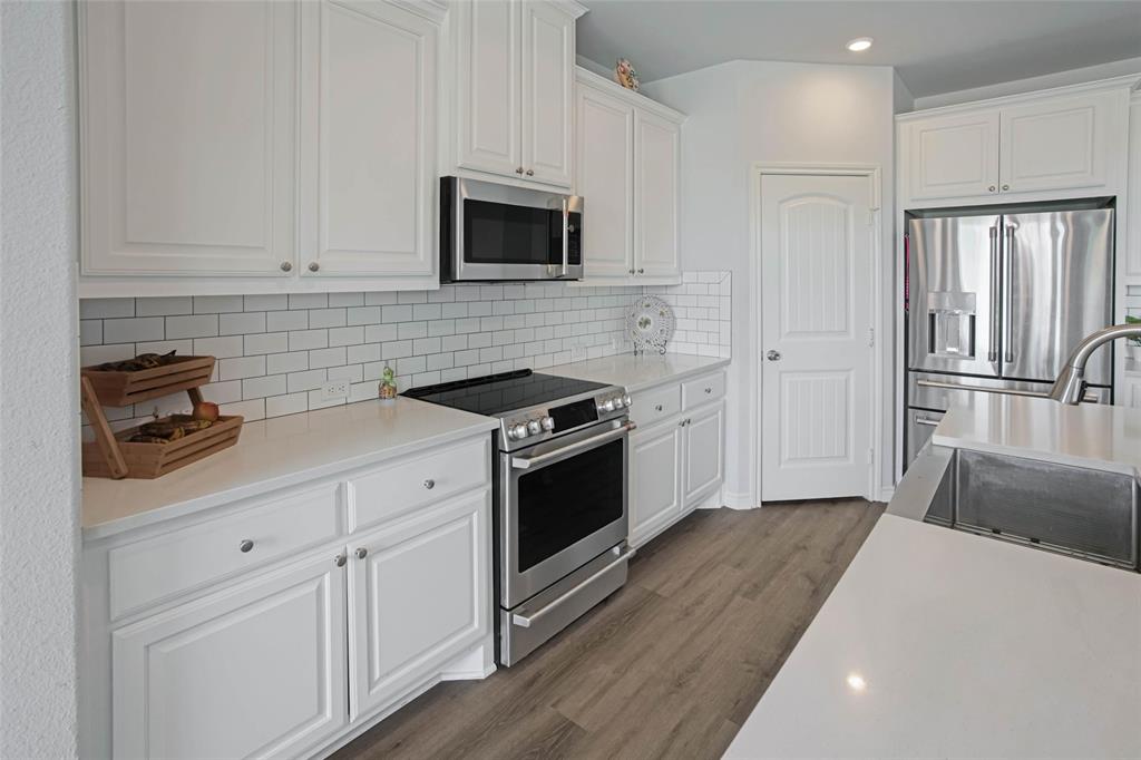 475 Massey Road Gunter, TX 75058 - Photo 16 of 34 Modern kitchen featuring white shaker cabinetry, stainless steel appliances, a subway tile backsplash, light-toned countertops, and wood-finish flooring