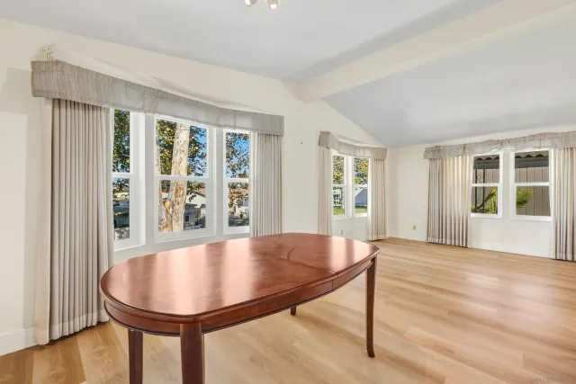 an empty room with wooden floor chandelier and windows
