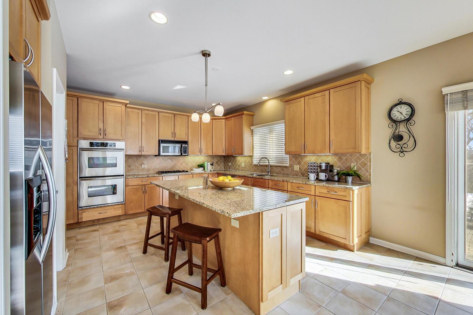 1927 Sheridan Road Buffalo Grove, IL 60089 - Photo 6 of 29 a kitchen with stainless steel appliances kitchen island granite countertop a refrigerator a stove a sink a dining table and chairs with wooden floor