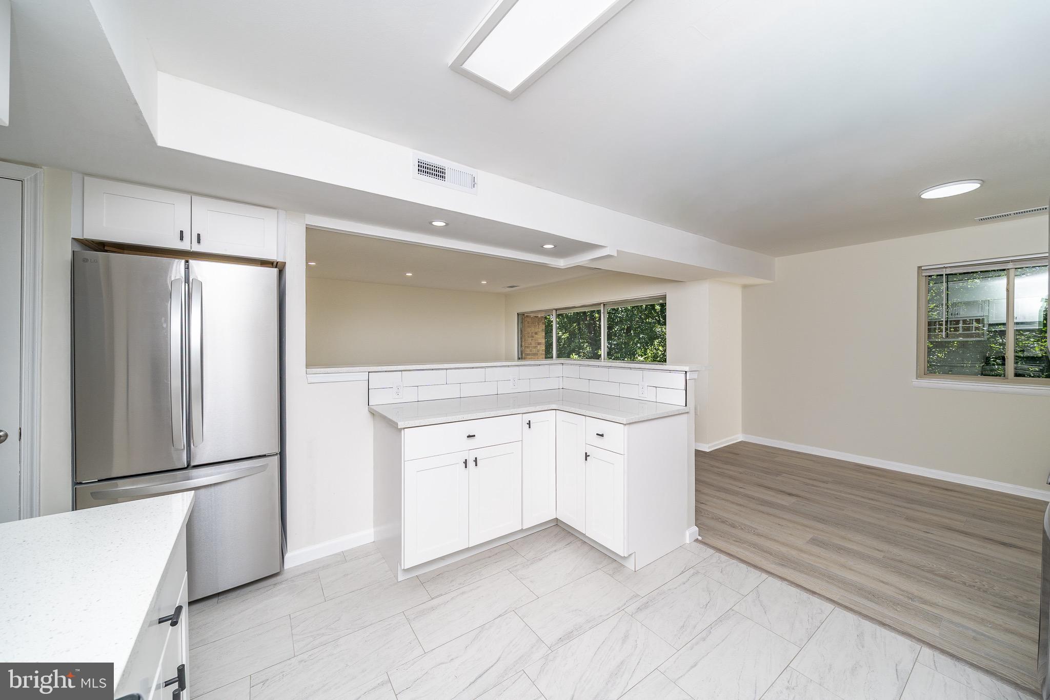 9910 Walker House Road, Unit 99104 Gaithersburg, MD 20886 - Photo 16 of 32 a large white kitchen with a refrigerator and a sink