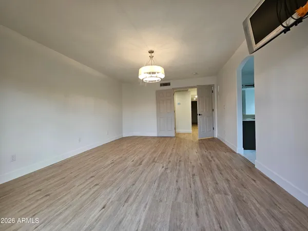 a view of an empty room with wooden floor and a window